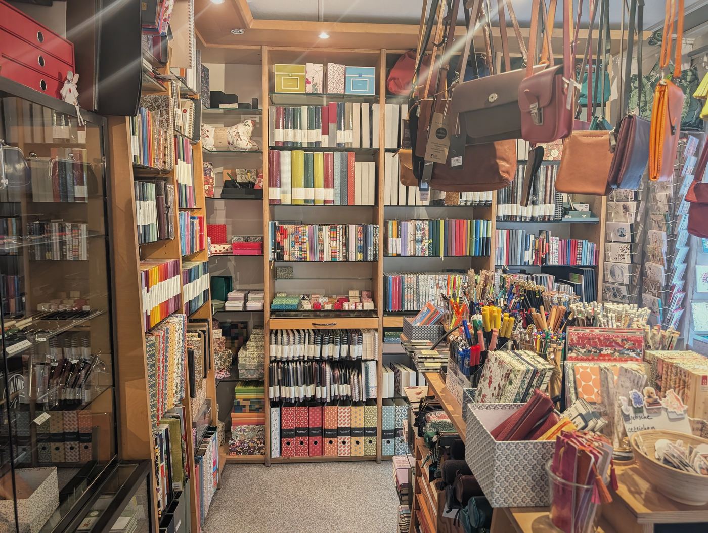 Regale voller Notizbücher, Ordner und Schachteln, davor Ledertaschen
